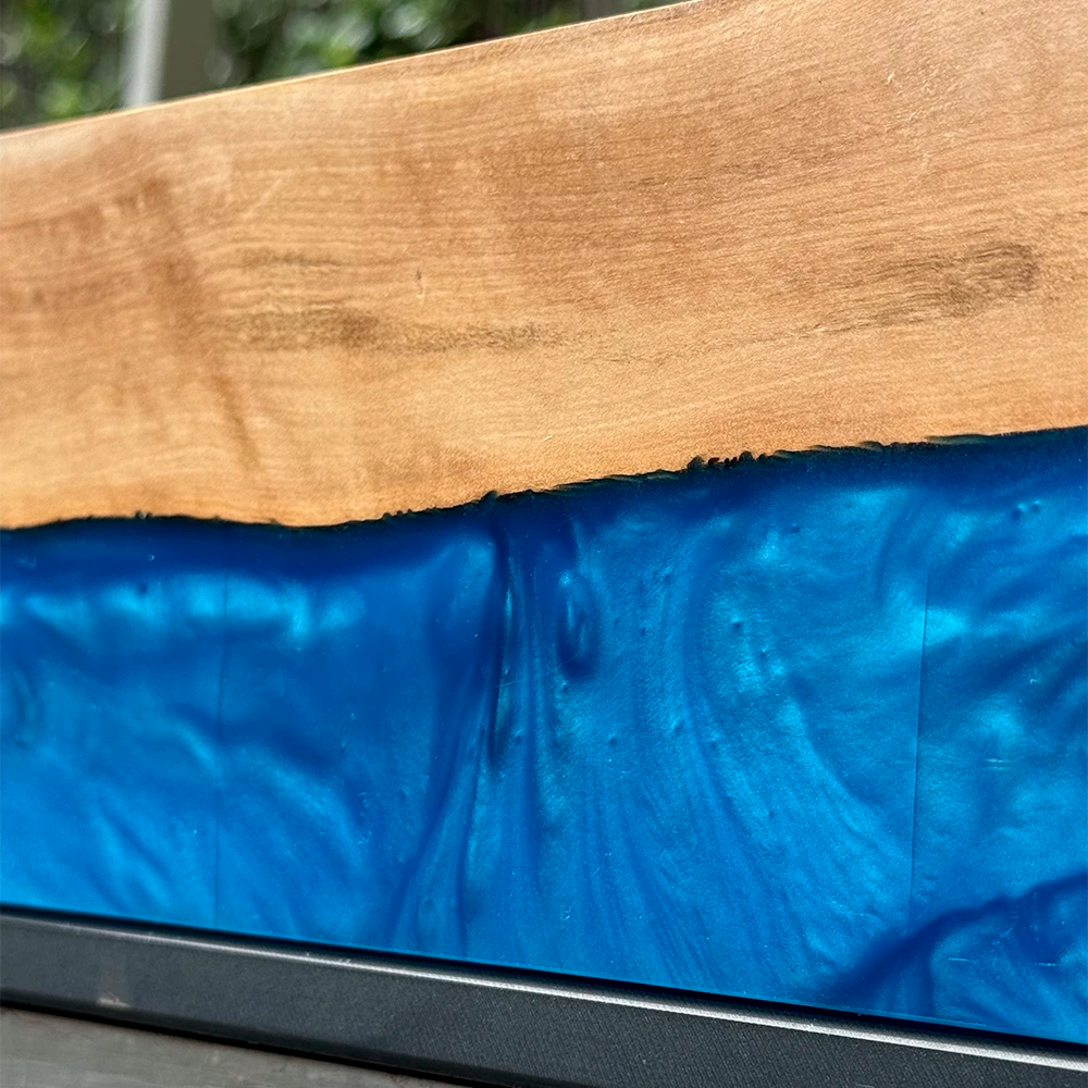 Detalle del río de resina epóxica azul perlada sobre madera de olivo